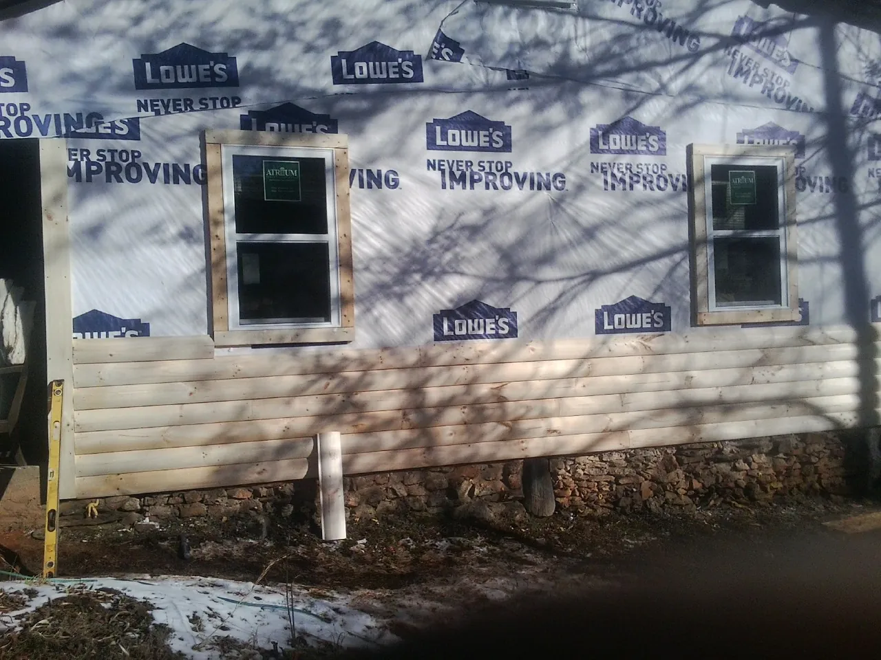 House wrap and new log siding going up on an exterior wall in Myakka City
