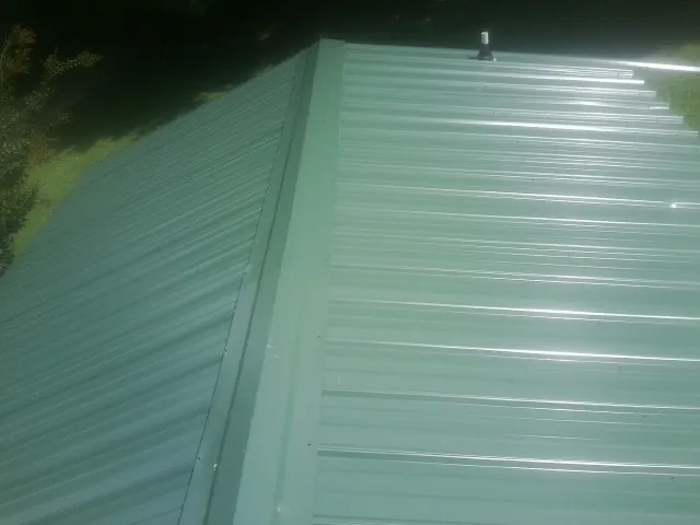 New green metal panels meeting at the ridge of a roof — Flat Roof Repair work by our crew in Myakka City