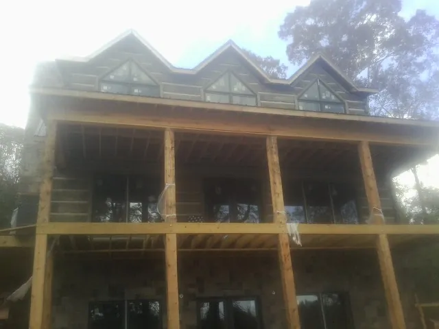 Dormers and porch framing on a large log home under construction — Roof Coating work by our crew in Myakka City