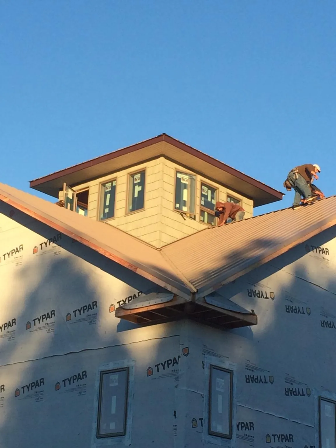 Roofers working around a rooftop cupola on a new metal roof at sunset — Roof Waterproofing in Myakka City by Roofing Brothers